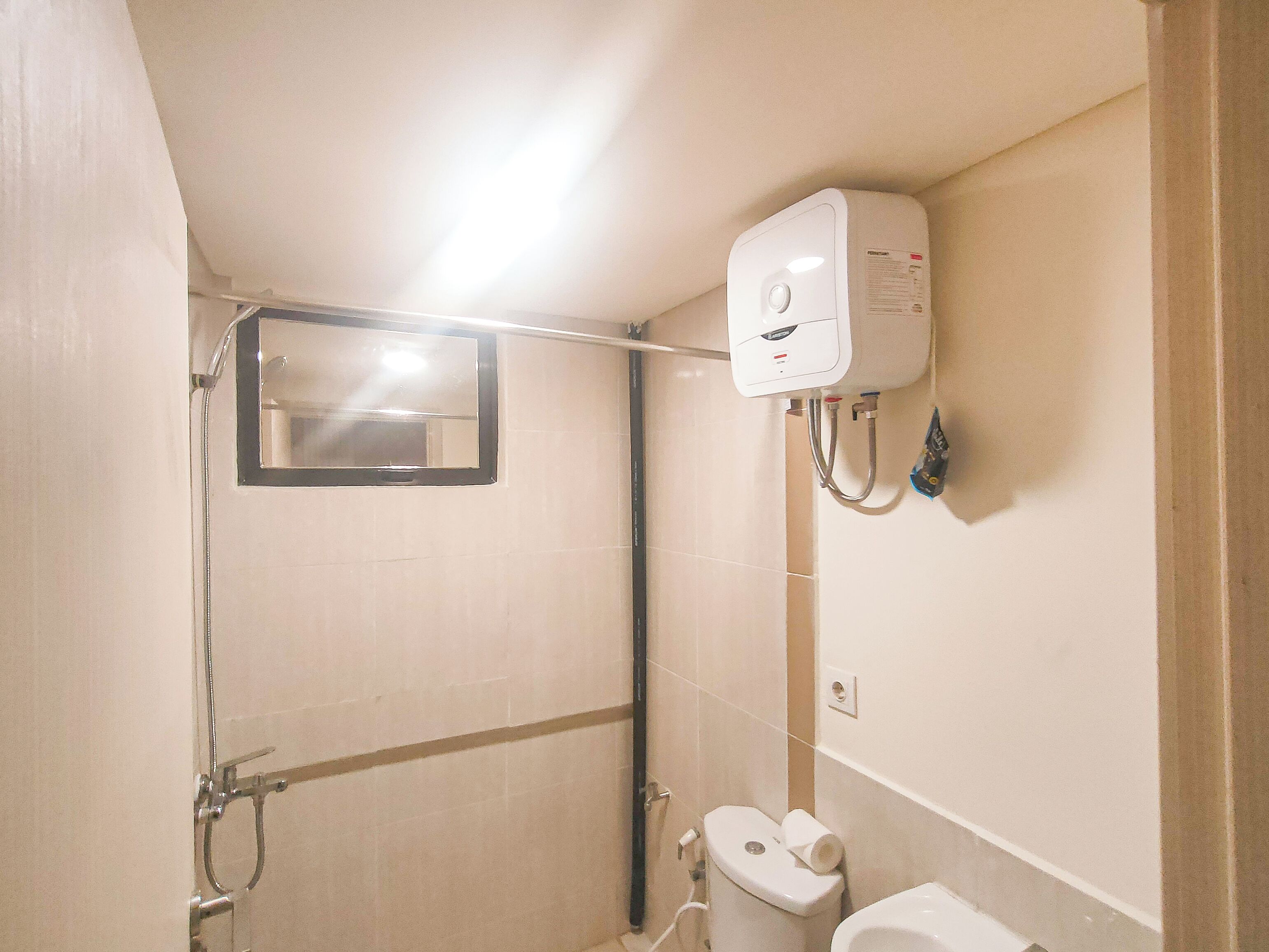 Ein kleines Badezimmer mit Dusche, Toilette und einem an der Wand montierten Handtrockner.