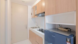Una cocina compacta con armarios de madera, un lavamanos empotrado y un refrigerador pequeño.