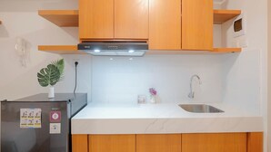 A modern kitchen with wooden cabinets, a stainless steel sink, and a built-in range hood. - Simply Look And Cozy Studio Apartment Tokyo Riverside Pik 2 (Teluknaga)
