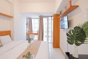 Relax in a serene space with a made bed, flat-screen TV, and a view of the building's exterior.