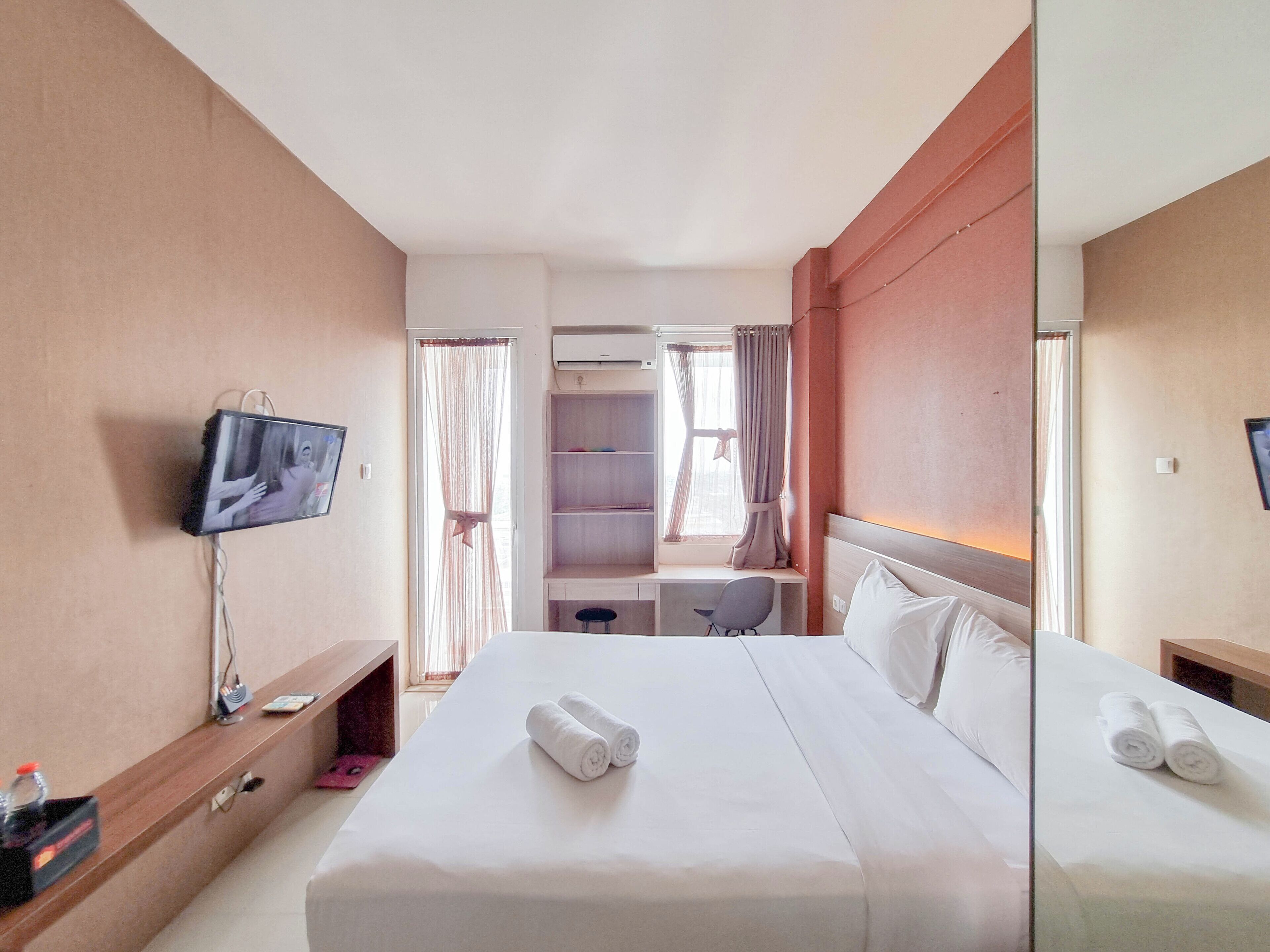 A hotel room with a bed, a TV, a desk, and a wardrobe.