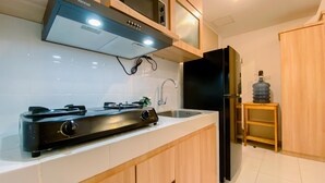 A modern kitchen with a gas stove, microwave, and black refrigerator. - Nice View And Cozy 1Br Apartment At Tokyo Riverside Pik 2 (Teluknaga)