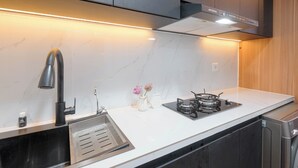 A modern kitchen with a stainless steel sink, a gas stove, and a built-in oven. - Modern Studio At Tokyo Riverside Pik 2 Apartment (Teluknaga)