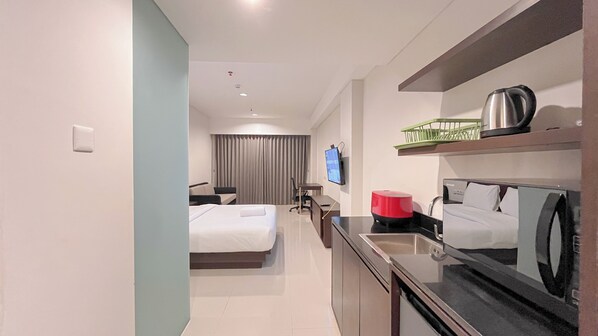 Una habitación de hotel con dos camas, un escritorio, un televisor, una cafetera y un microondas.