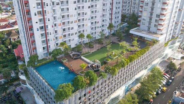 Un edificio de gran altura con piscina en la azotea, terrazas ajardinadas y un diseño arquitectónico moderno.