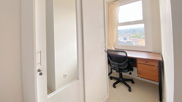Una habitación con escritorio, silla y ventana con vista a la ciudad.