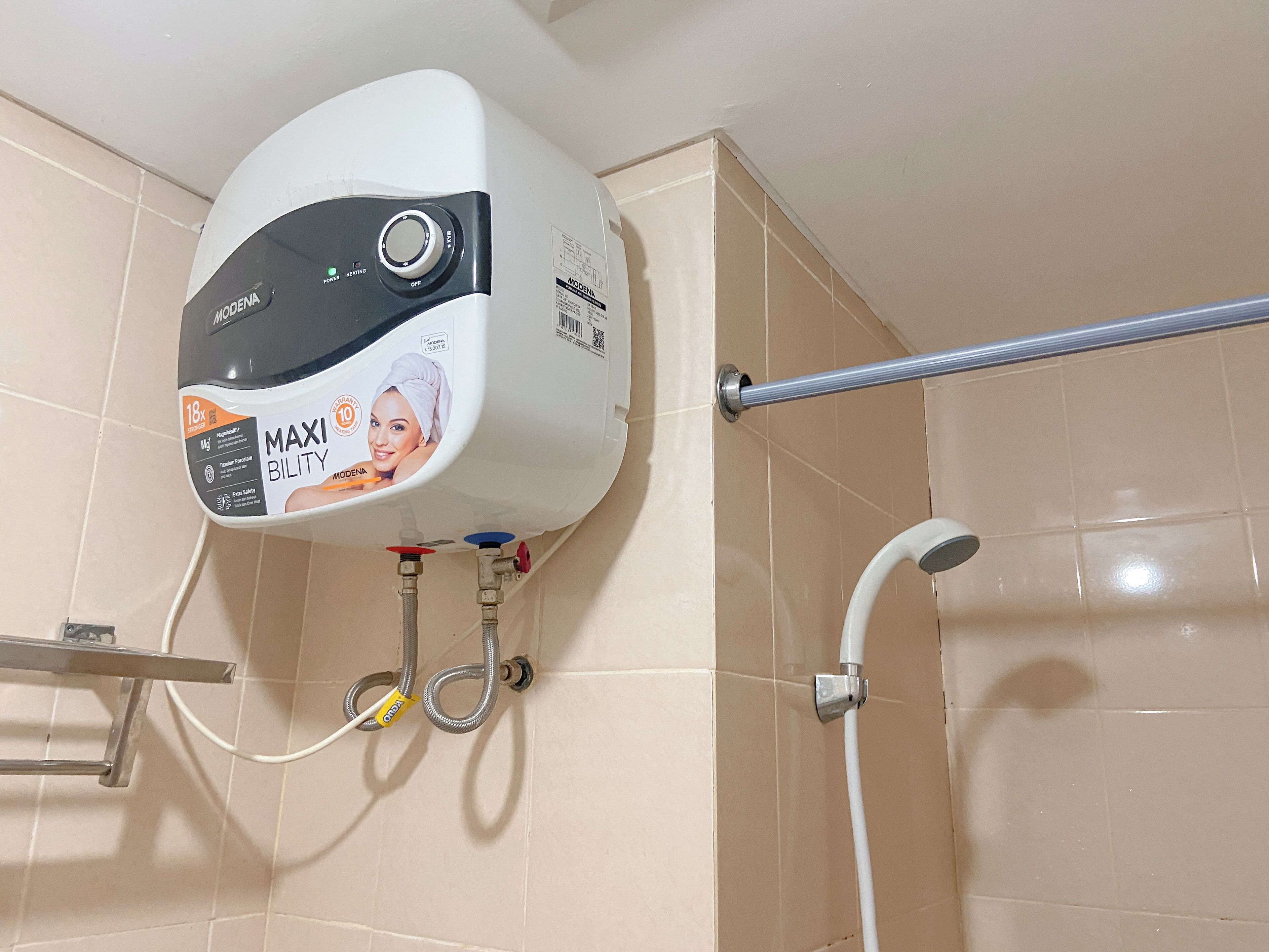 Une salle de bain équipée d’un chauffe-eau mural, d’une pomme de douche et d’un porte-serviettes.