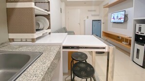 A compact kitchen with a granite countertop, a built-in dishwasher, and a small dining area with stools. - Simply And Cozy 2Br Apartment At Parahyangan Residence (Bandung)