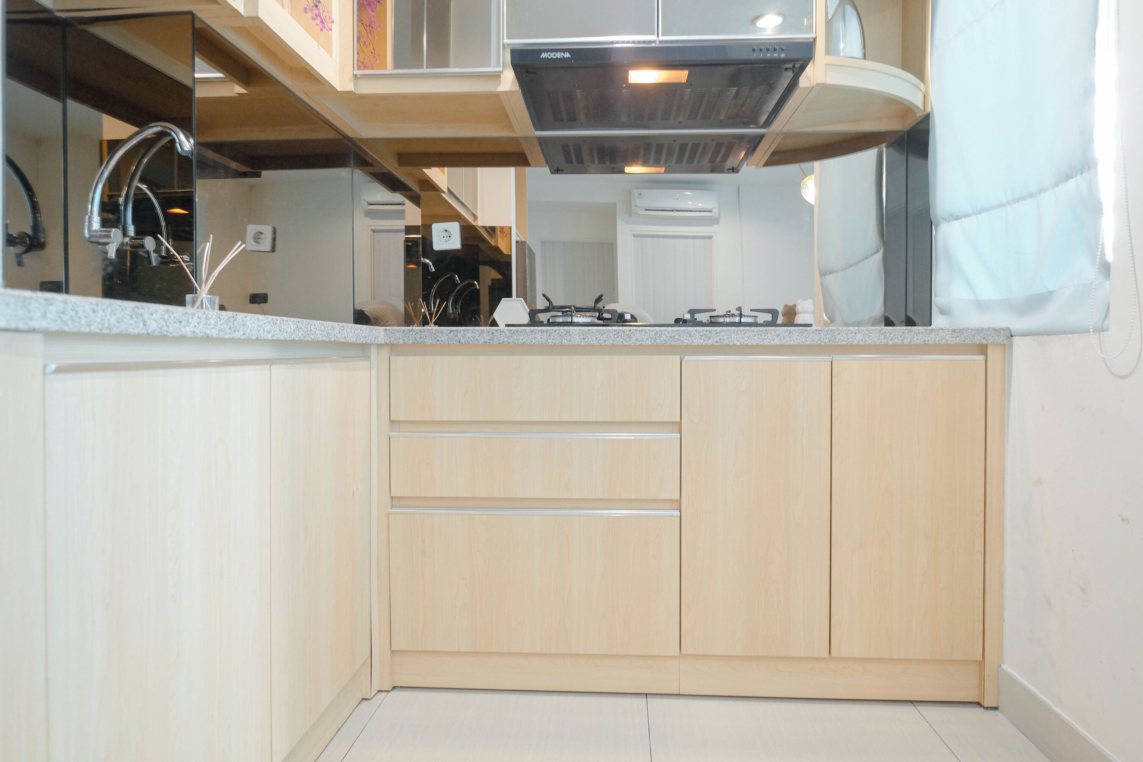 Una cucina moderna con mobili in legno, un piano di lavoro in granito e una cappa aspirante in acciaio inossidabile.