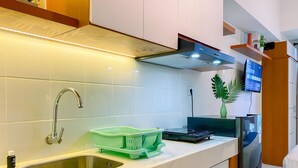 A modern kitchen with a stainless steel sink, a green dish rack, and a built-in stove. - Relaxing and Comfortable Studio at Tokyo Riverside PIK 2 Apartment  (Teluknaga)