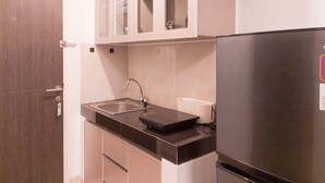 A compact kitchen with a stainless steel refrigerator, a sink, and a countertop.