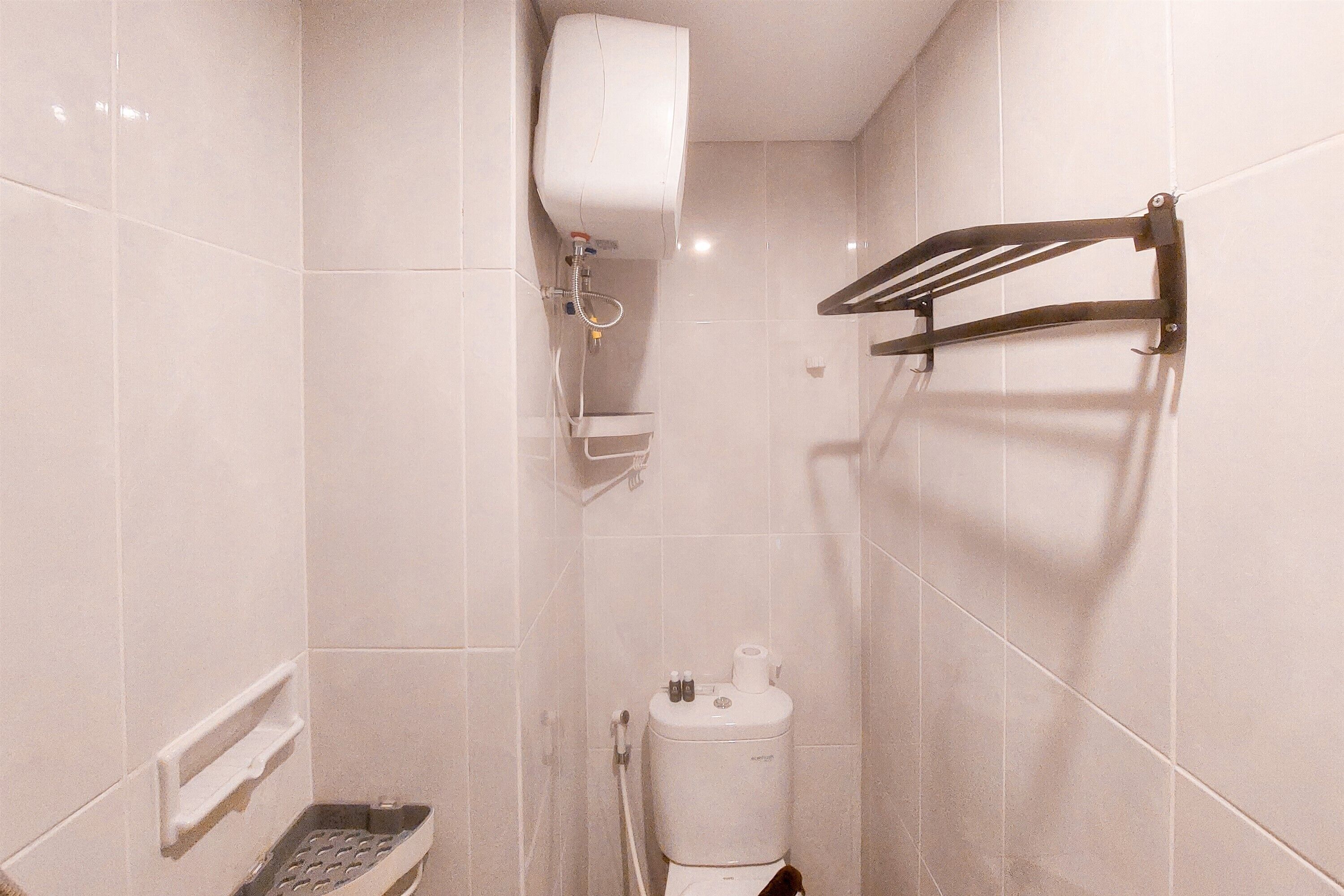 A small, tiled bathroom with a toilet, a hand dryer, and a towel rack.
