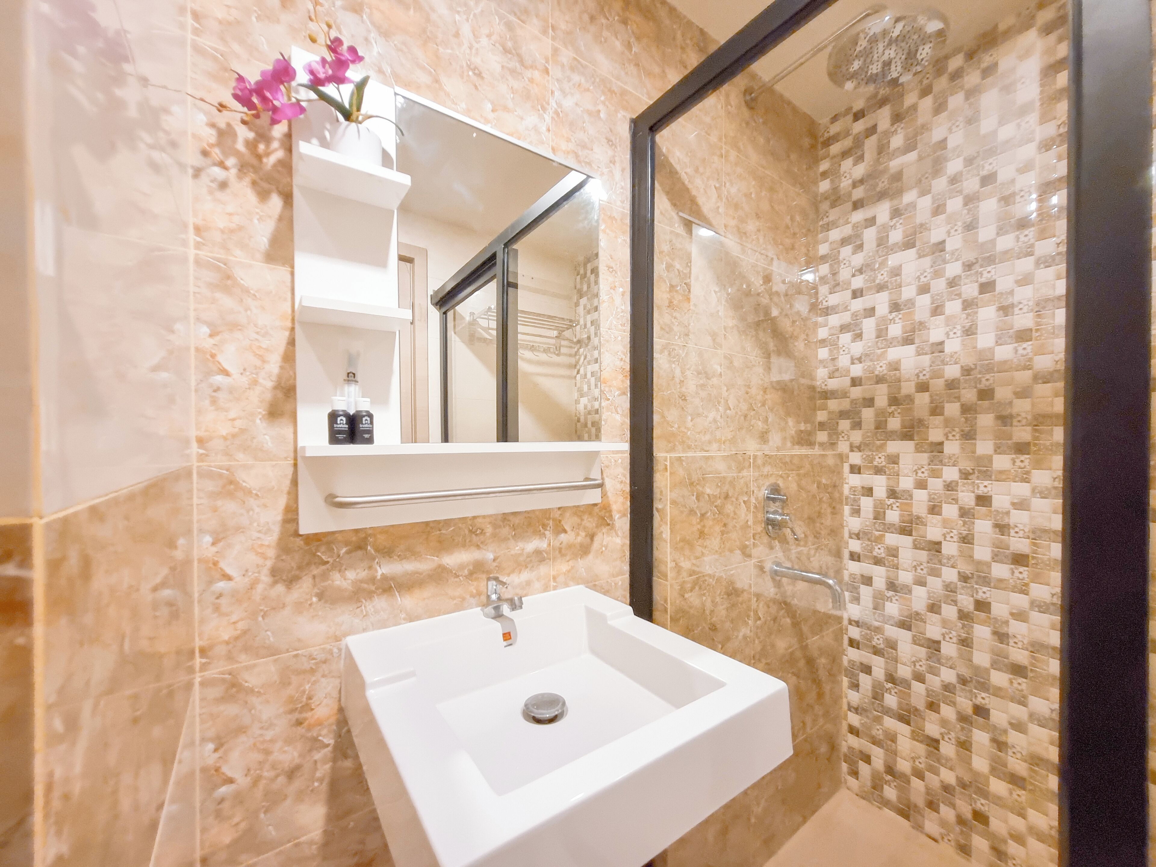 Une salle de bain avec un lavabo blanc, un miroir et une douche aux carreaux de mosaïque.