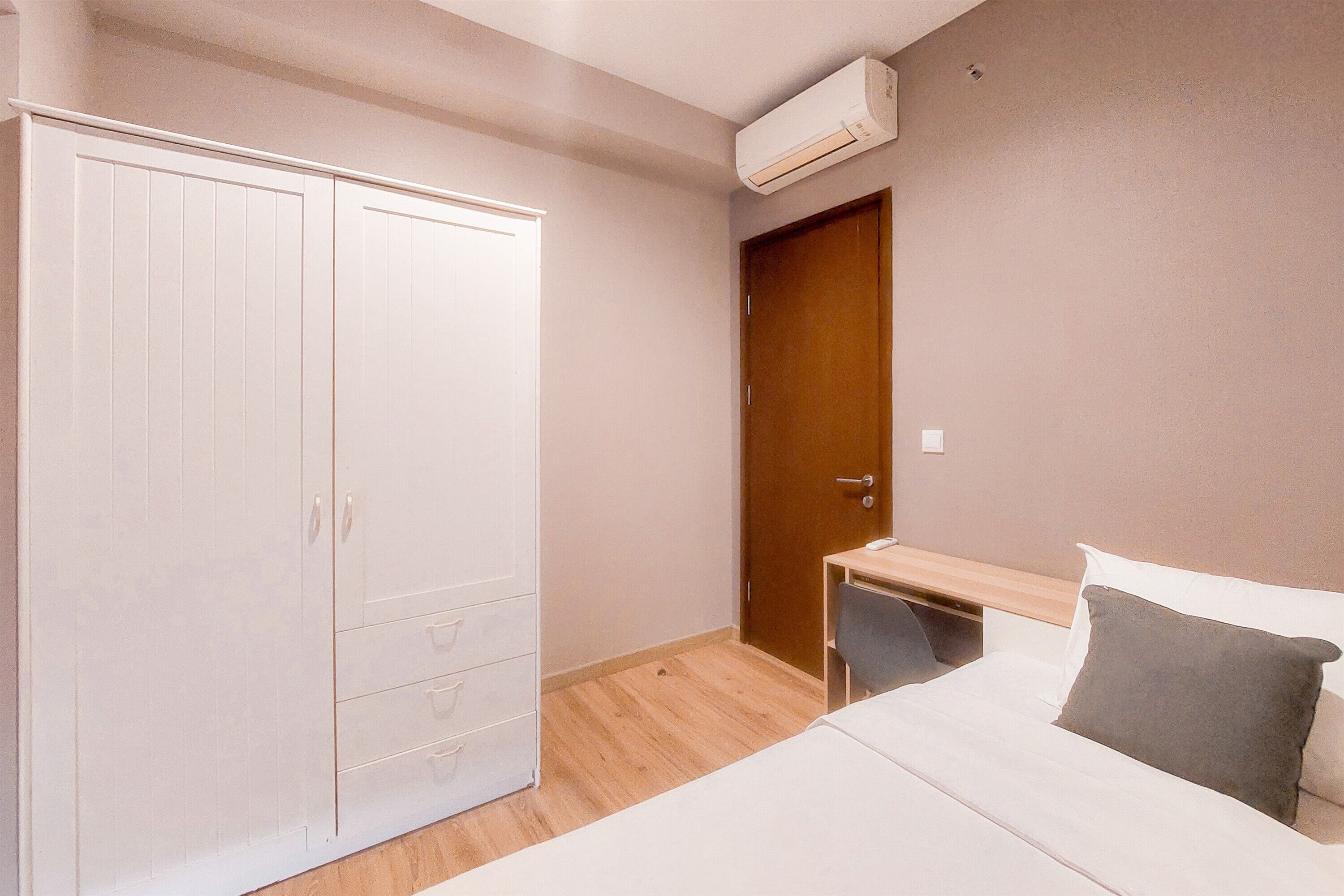 Ein Schlafzimmer mit Bett, Schrank, Schreibtisch und einer Tür.