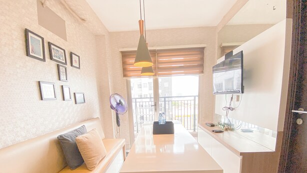 A modern living room with a sofa, a flat-screen TV mounted on the wall, a ceiling fan, and a view of the outside balcony. - Spacious 3Br At Mekarwangi Square Cibaduyut Apartment (Bandung)