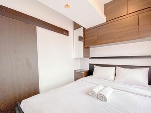 Habitación de hotel moderna con una cama grande, cabecera de madera y armarios empotrados.