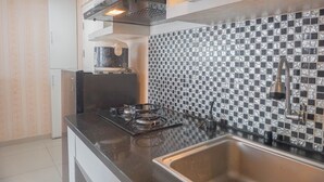 Une cuisine équipée d’une cuisinière à gaz, d’un évier en acier inoxydable et d’un crédence ornée d’un motif noir et blanc.
