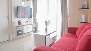 Un salon moderne avec un téléviseur à écran plat, un canapé, une table basse et un meuble.