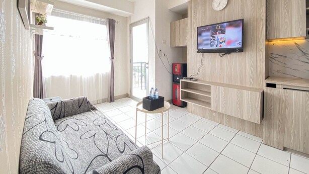 Ein modernes Wohnzimmer mit einer Couch, einem an der Wand befestigten Fernseher, einem kleinen Tisch und einem roten Gerät in der Ecke.
