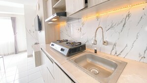 Eine moderne Küche mit Edelstahlspüle, Gasherd und eingebautem Backofen. Oberhalb des Herdes befindet sich ein Holzschrank und ein an der Wand befestigter Fernseher.