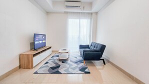 A modern living room with a flat-screen TV, a sofa, a small table, and a patterned rug.
