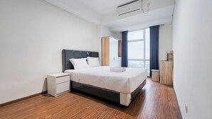 A modern hotel room with a bed, a nightstand, a wardrobe, and a large window with curtains.