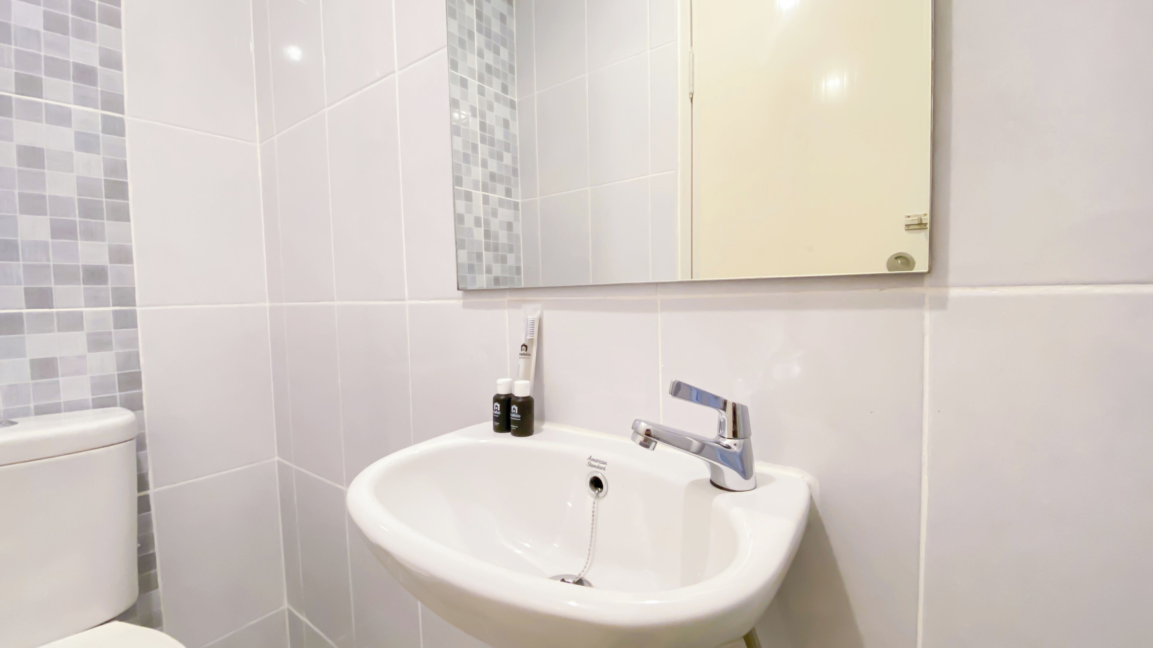 A bathroom with a white sink, a mirror, and a toilet.