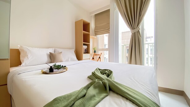 Una camera d'albergo con un letto grande, un comodino, una piccola sedia e una finestra con tende.