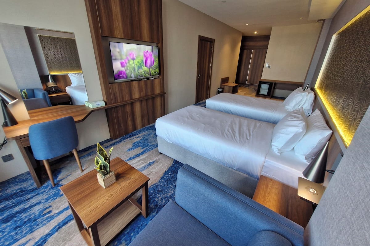 Une chambre d’hôtel avec un lit, un bureau, une chaise, une télévision et une petite table sur laquelle est posée une plante.
