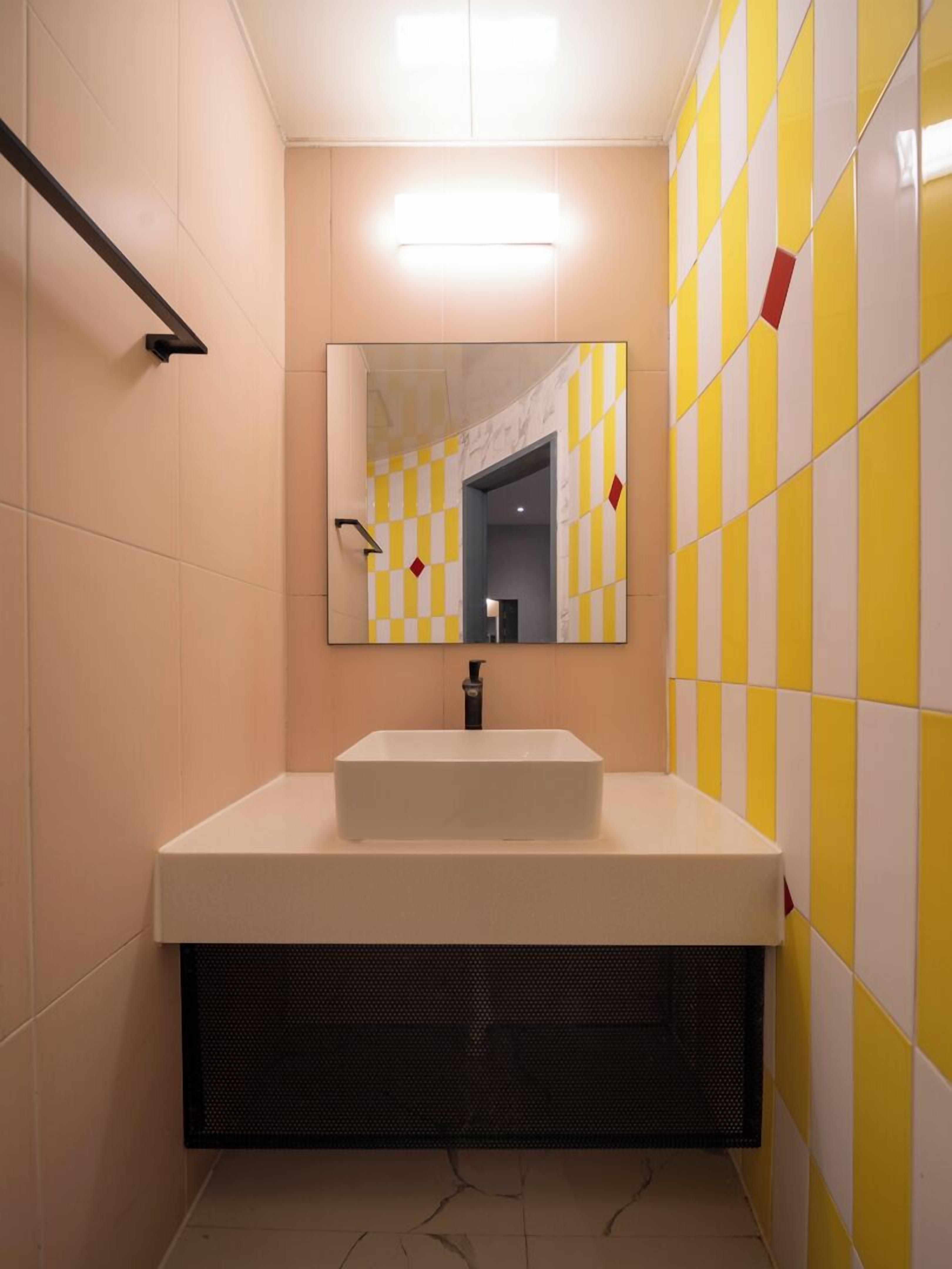 A bathroom with a white sink, a mirror, and yellow and white checkered tiles.