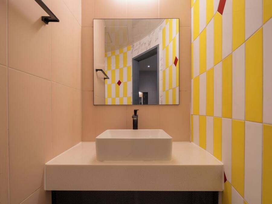 A bathroom with a white sink, a mirror, and yellow and white checkered tiles.