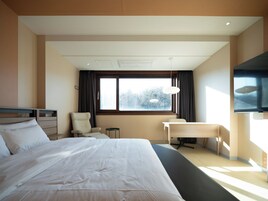 Una habitación de hotel moderna con una cama grande, un escritorio, una silla y un televisor.
