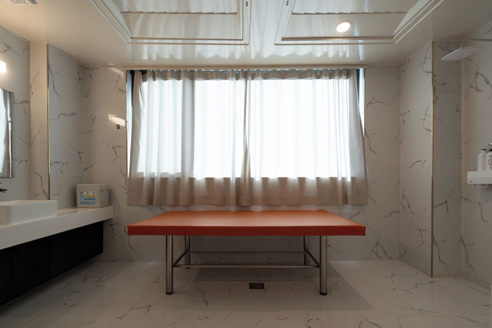 Un baño con piso de mármol, lavamanos blanco, espejo, tocador y zona de ducha.