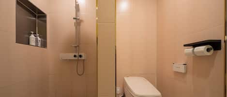 Baño con ducha, inodoro y estante con artículos de aseo.