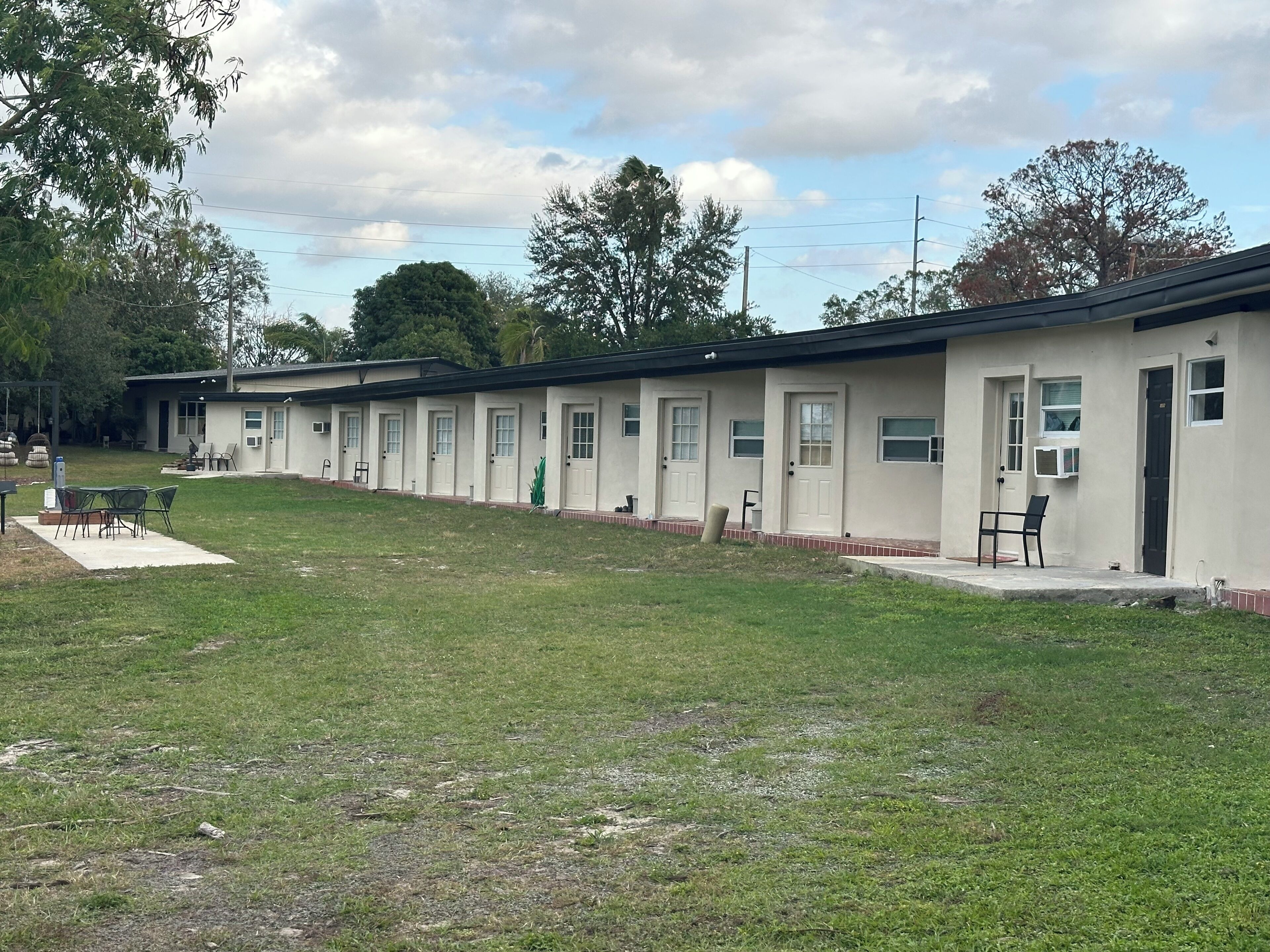 A row of motel rooms with a grassy lawn in front.