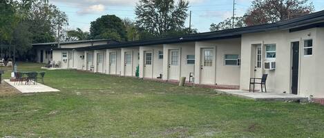A row of motel rooms with a grassy lawn in front.