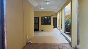 A corridor with yellow walls, a tiled floor, and a ceiling with recessed lighting.