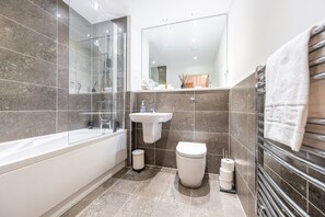 Une salle de bain moderne équipée d’une baignoire, d’un lavabo, de toilettes et d’une douche à parois de verre.