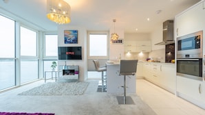 Een moderne keuken met een bar, grote ramen en uitzicht op zee.