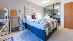 Een moderne slaapkamer met een groot bed, een bureau, een stoel en een kledingkast.