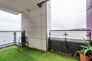 Enjoy the ocean view from this balcony with a chair and a potted plant.