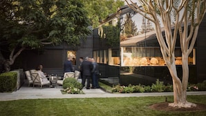 An outdoor dining area with a modern building, a tree, and a well-maintained lawn. - Villa Colibri, by Vinifera Homes (Kenwood)