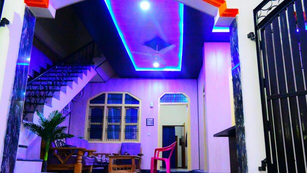 A multi-level house with a staircase, a ceiling fan, and a gated entrance. - Shraddha Guest House (Ayodhya)