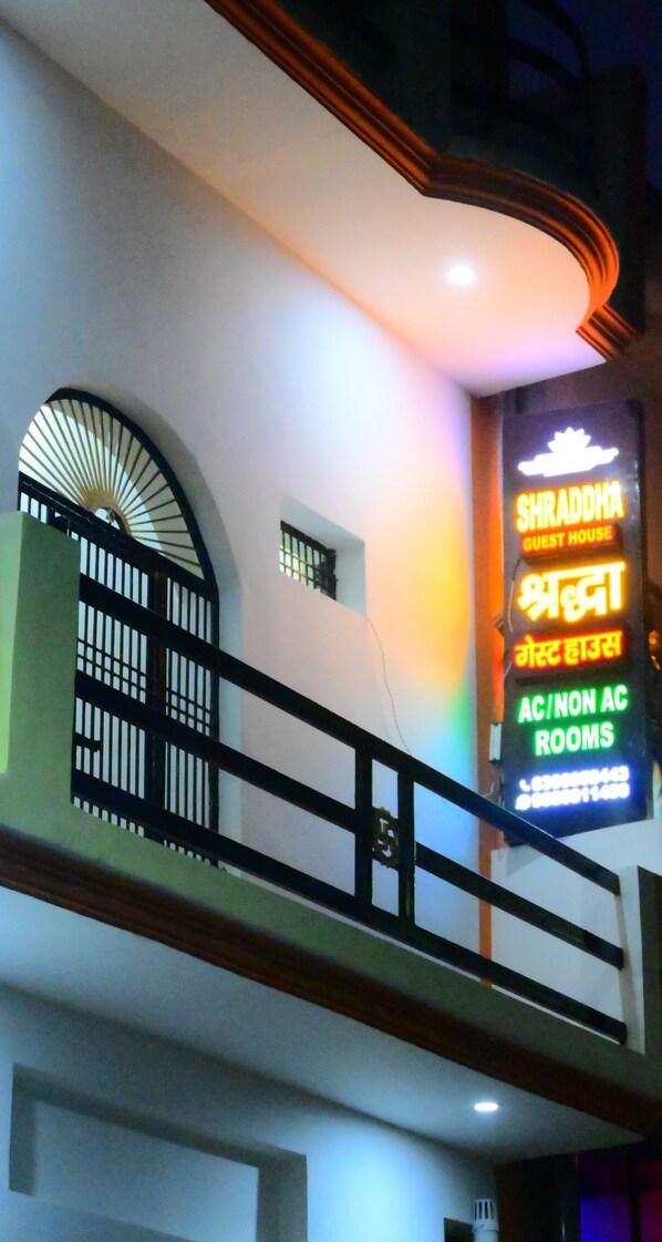 A hotel sign with multilingual text indicating guest rooms and contact numbers.