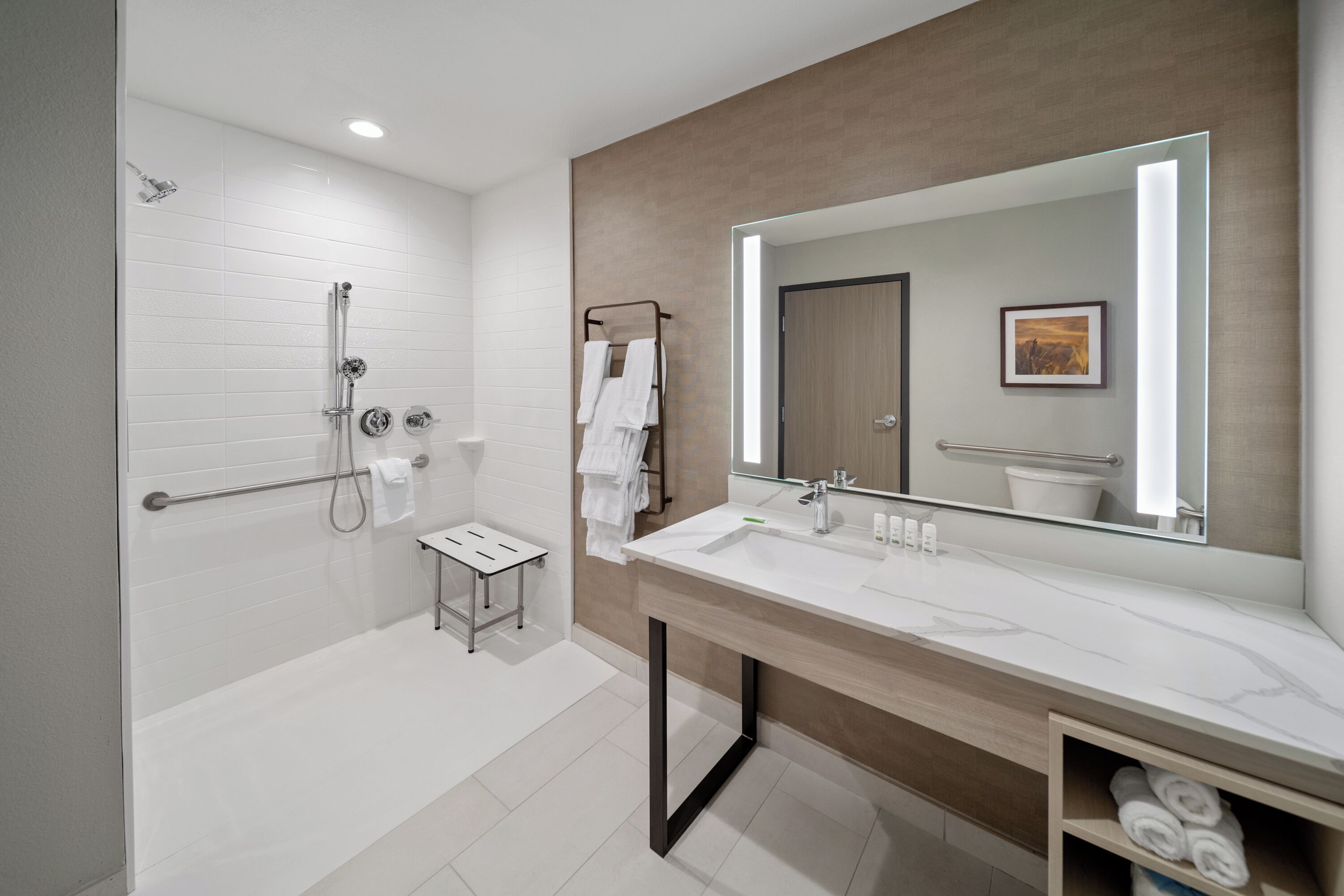A modern bathroom with a walk-in shower, a large mirror, and a vanity with a sink.