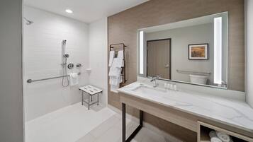 A modern bathroom with a walk-in shower, a large mirror, and a vanity with a sink.