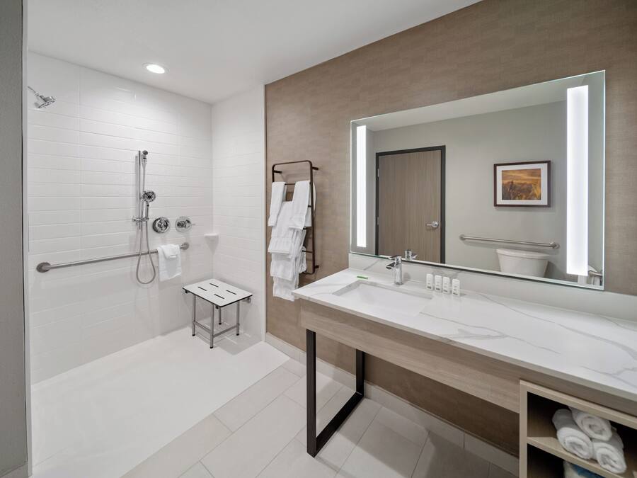 A modern bathroom with a walk-in shower, a large mirror, and a vanity with a sink.