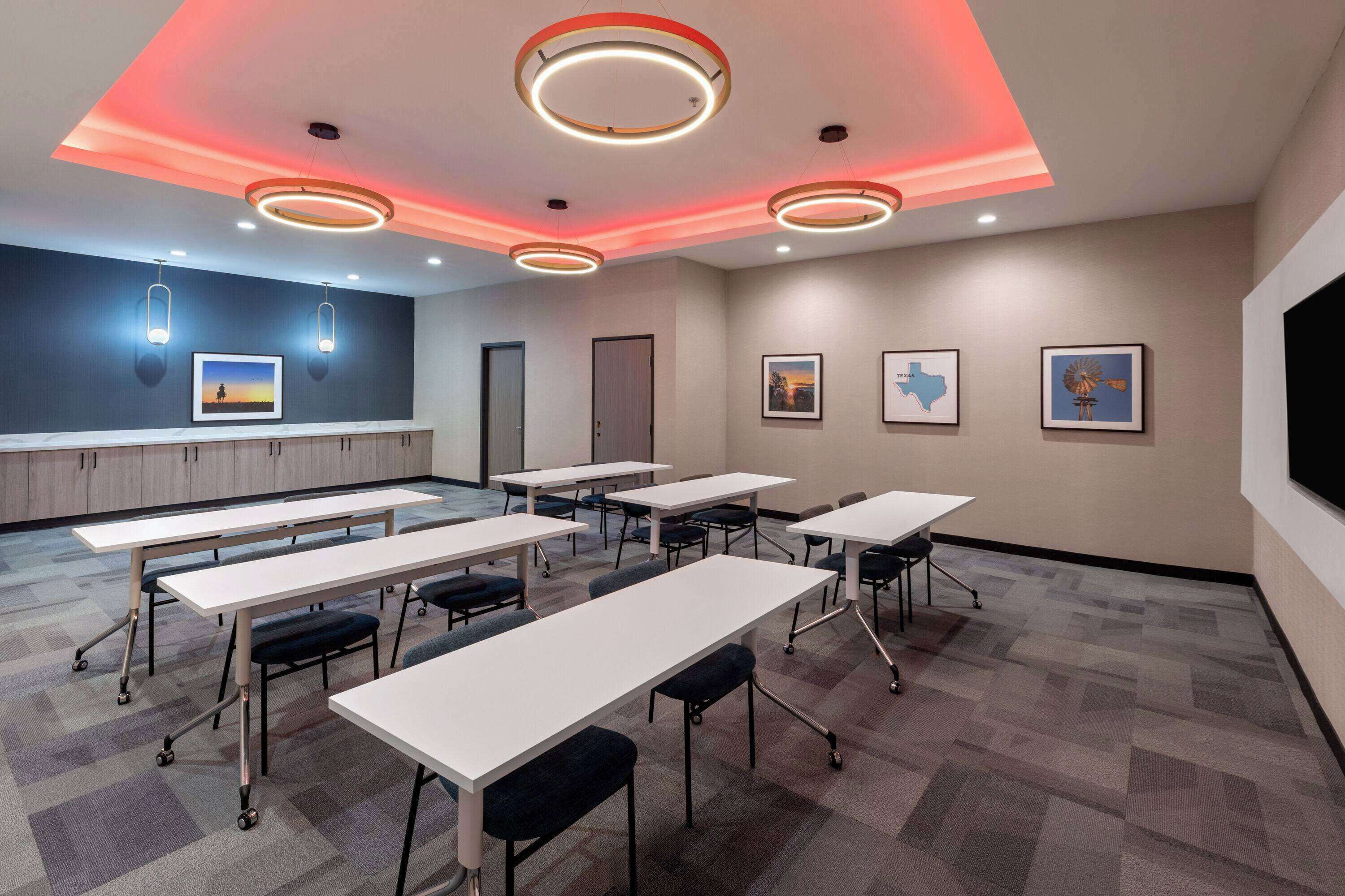 A conference room with white tables, black chairs, and a carpeted floor.