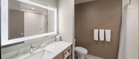 A modern bathroom with a large mirror, a sink, a toilet, and a shower area.