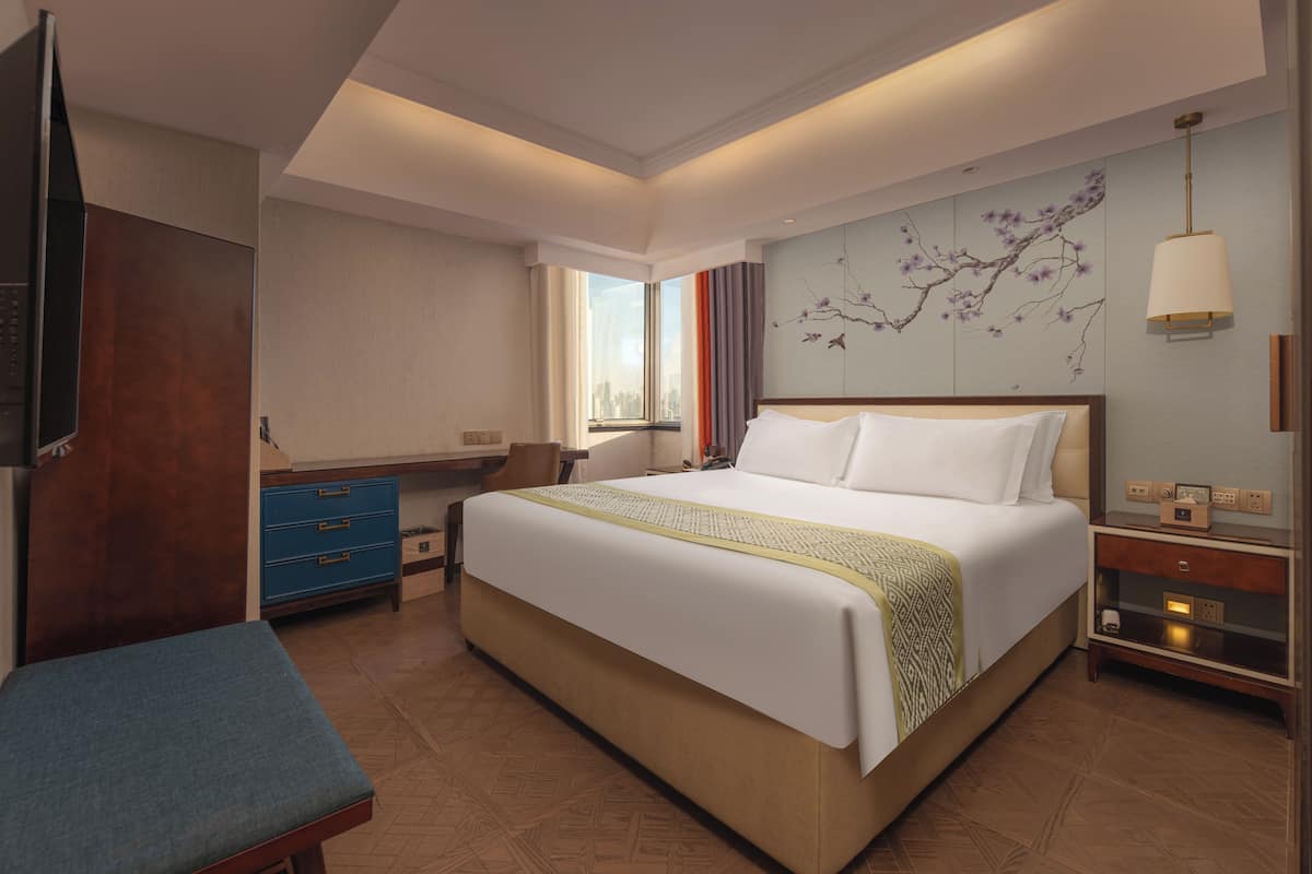 Een moderne hotelkamer met een groot bed, een bureau, een stoel en een televisie.
